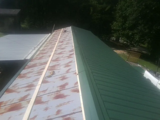 Old rusted panels beside newly installed green metal roofing — Wind Damage Roof Repair by Roofing Brothers in Toledo